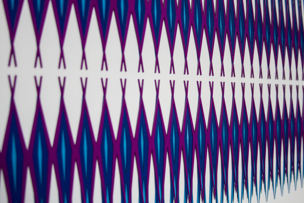 Panoramic geometric relief with repeated blue and magenta forms creating optical vibration and destabilized symmetry pattern by José Bonilla